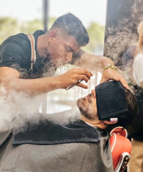 barber shaving mans beard with steam