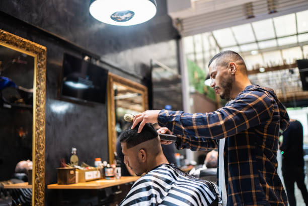 Hairdresser cutting the hair of a young man at the barber shop